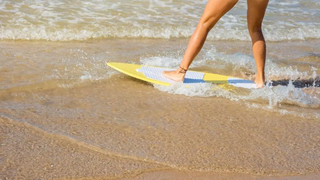 Beginner skimboarder on shallow water